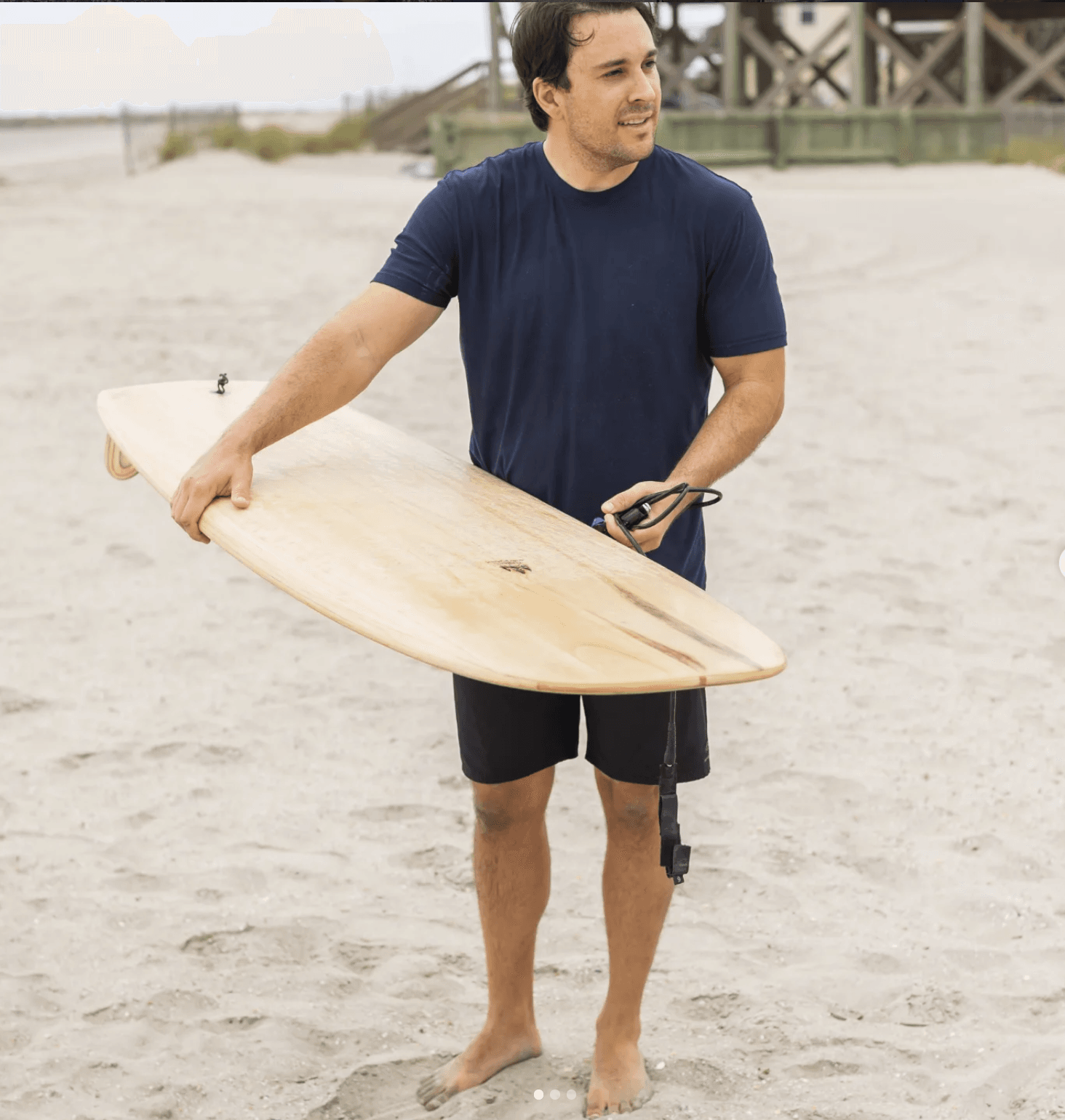 Builder con su tabla en la playa